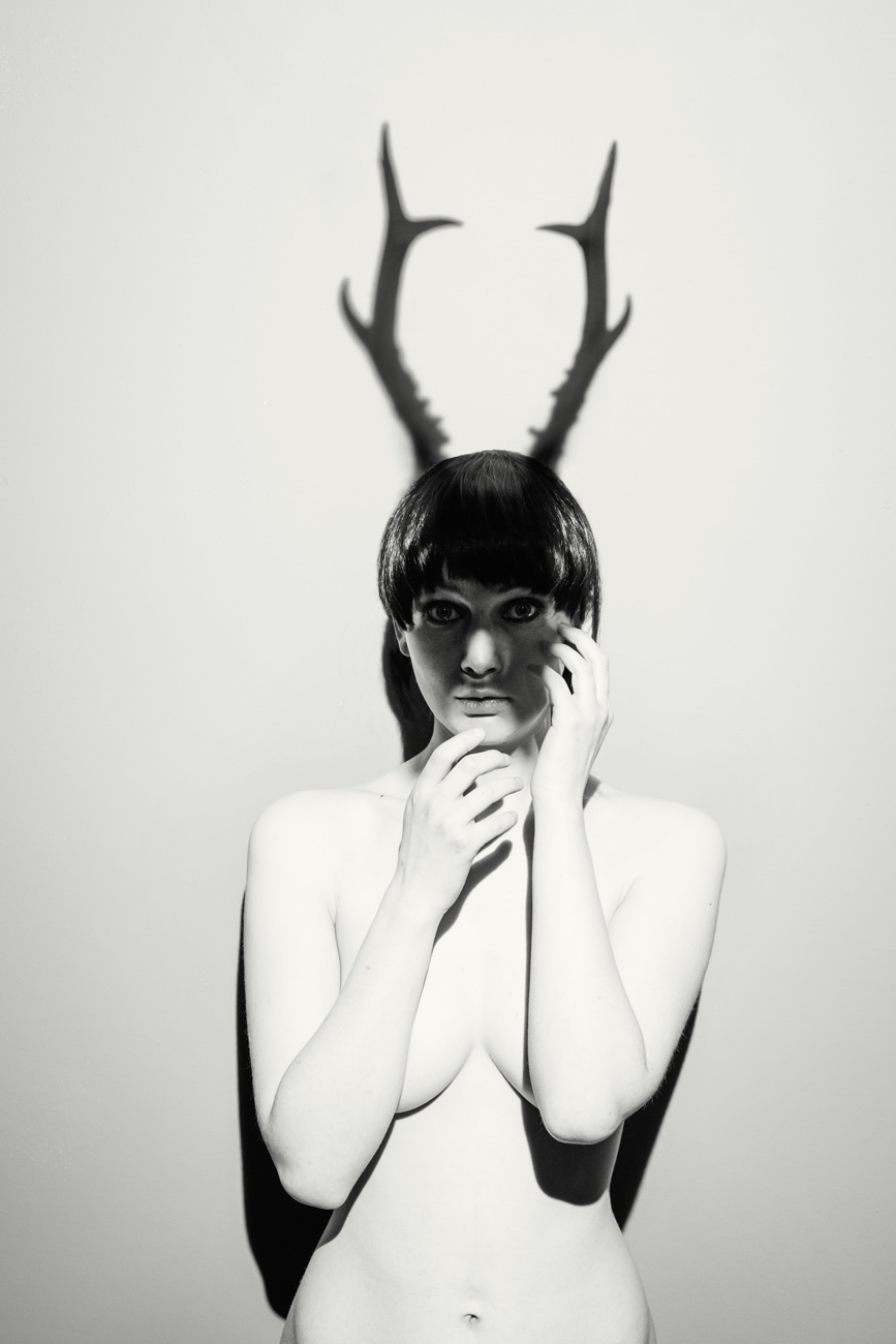 nude female model as mythical god cerynitis with the shadow of antlers